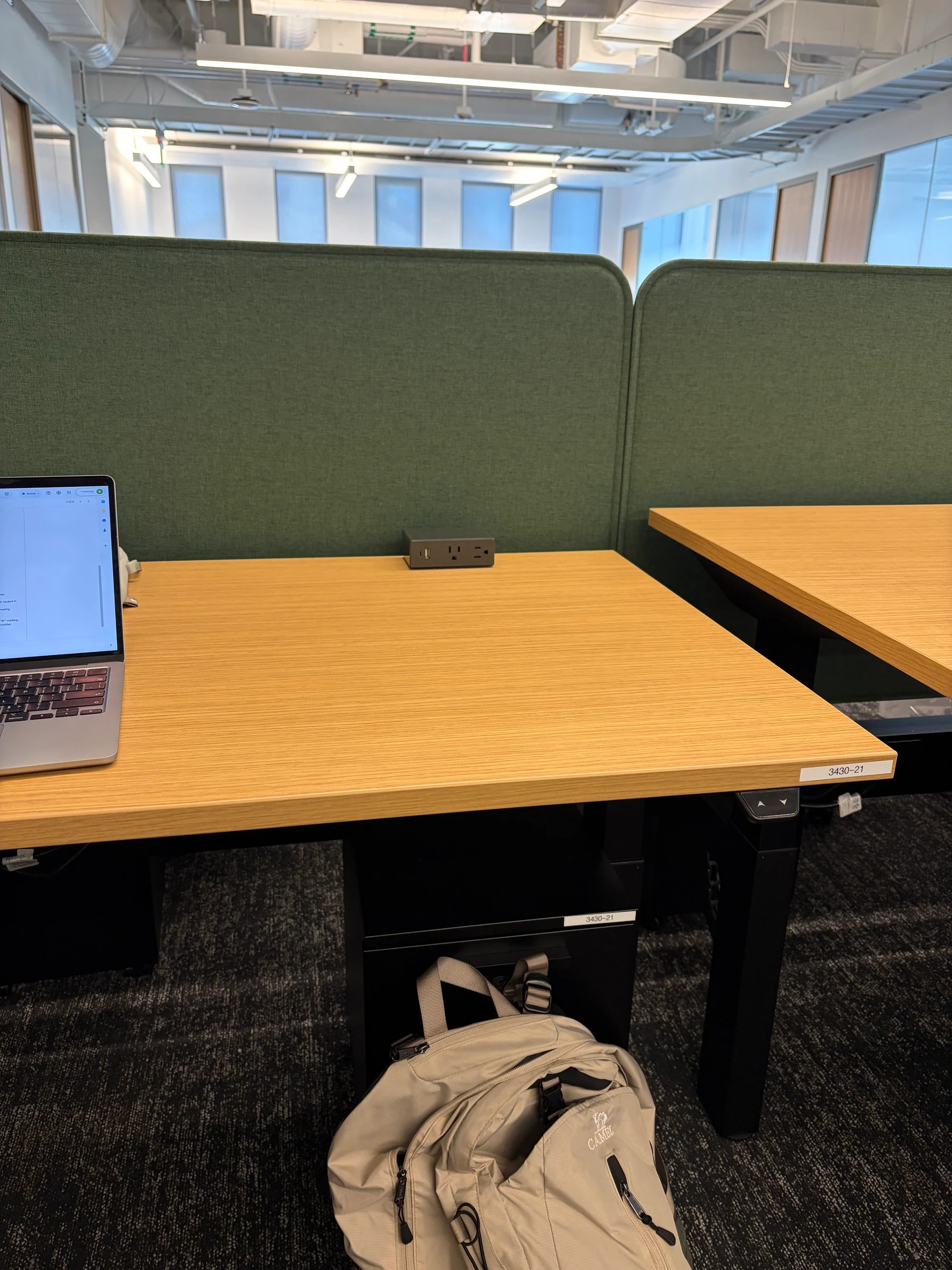 My desk at BAIR: a new wood-grain standing desk against a dark green partition